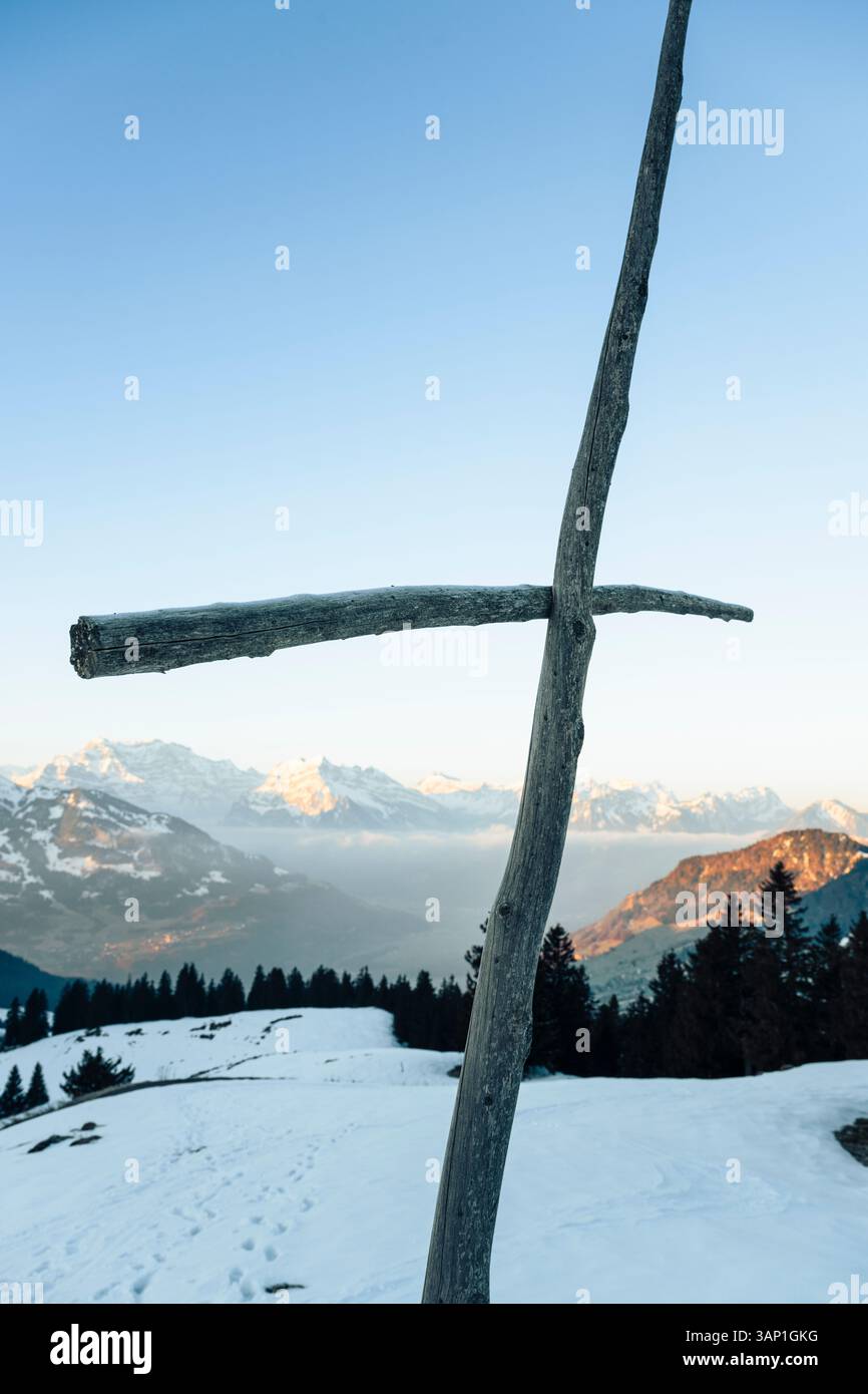 Una croce di legno di fronte al panorama delle Alpi Glariche innevate all'alba, San Gallo, Glarona, Svizzera Foto Stock