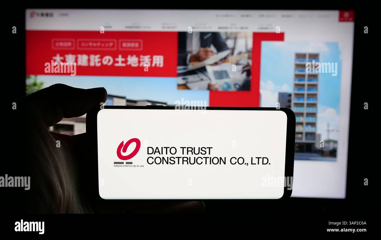 Stoccarda, Germania - 12-04-2024: Persona che detiene il cellulare con il logo della società Daito Trust Construction Company Ltd. Sullo schermo Foto Stock