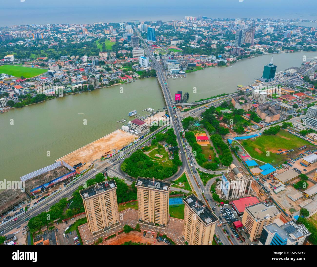 Vista aerea di un vivace paesaggio urbano con edifici moderni e un ponte su un fiume, Victoria Island, Nigeria. Foto Stock