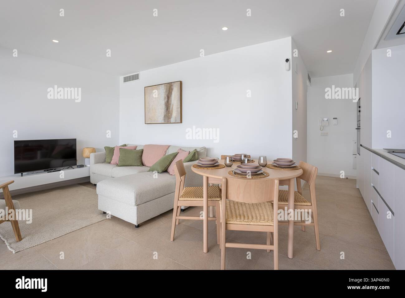 Lounge luminosa e aperta con arredi dai toni tenui, area pranzo compatta e opere d'arte a parete. Foto Stock