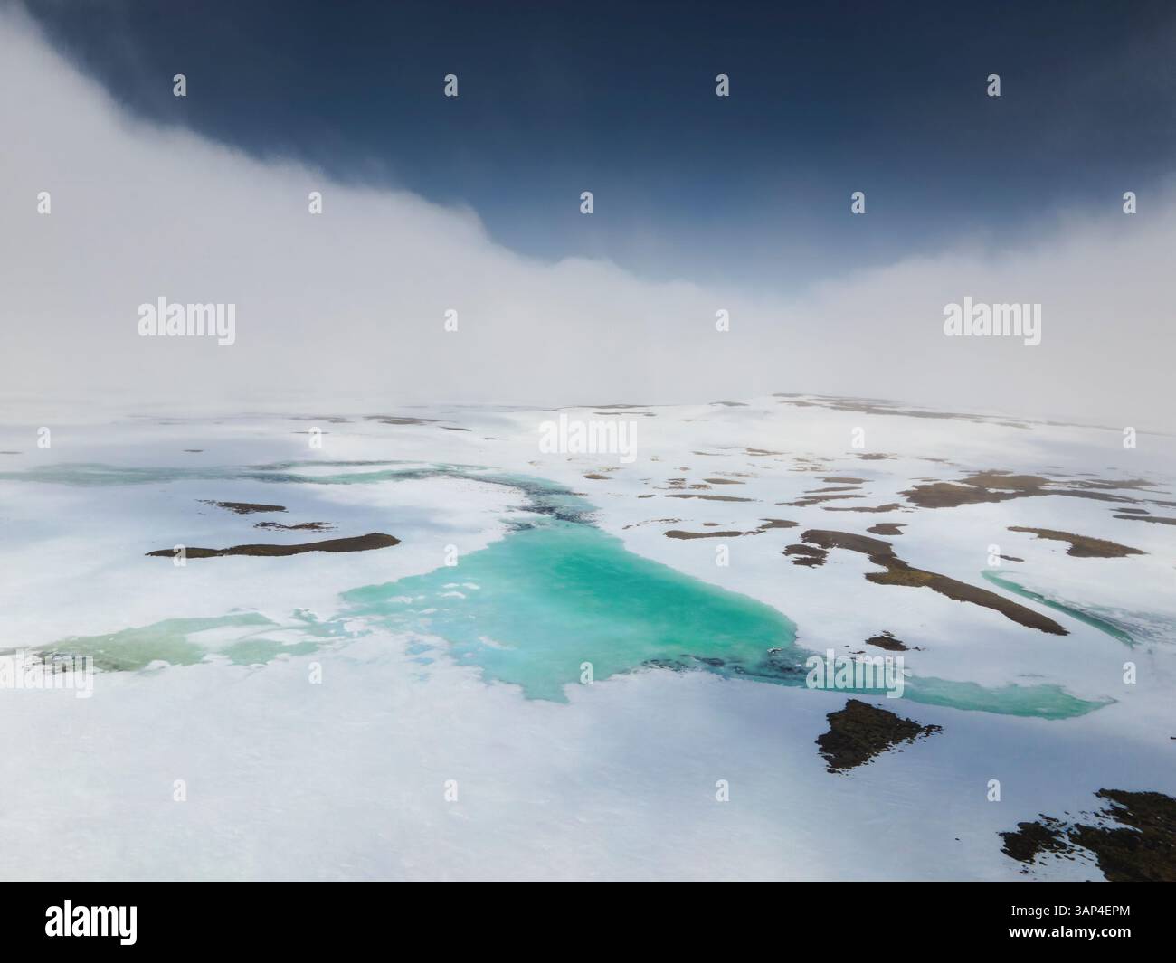 Vista aerea di un tranquillo lago glaciale circondato da neve e ghiaccio in uno splendido paesaggio artico, Holmavik, Islanda. Foto Stock