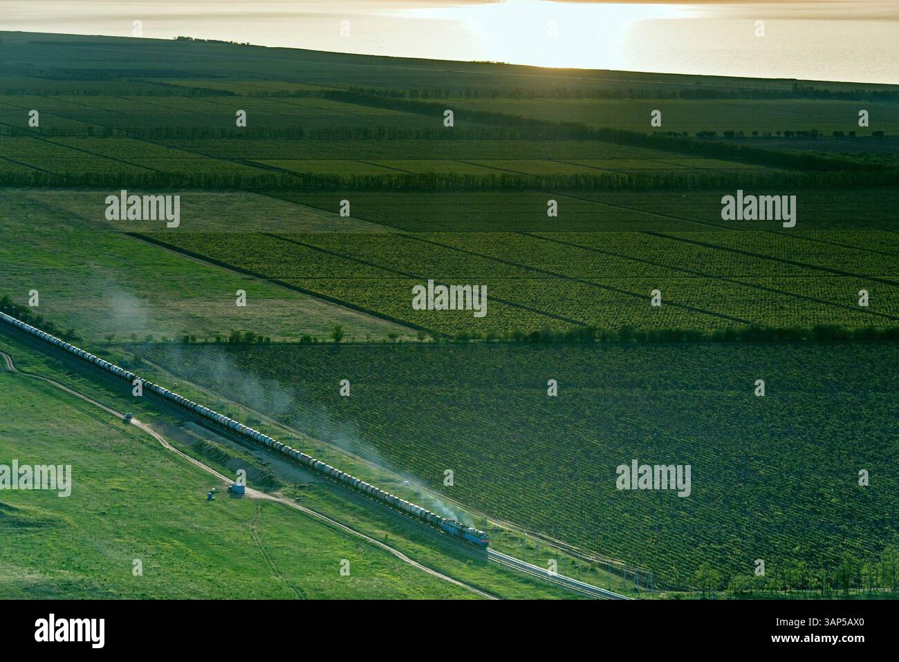 Vista aerea dei tranquilli campi agricoli con un treno che passa al tramonto, regione di Krasnodar, Russia. Foto Stock