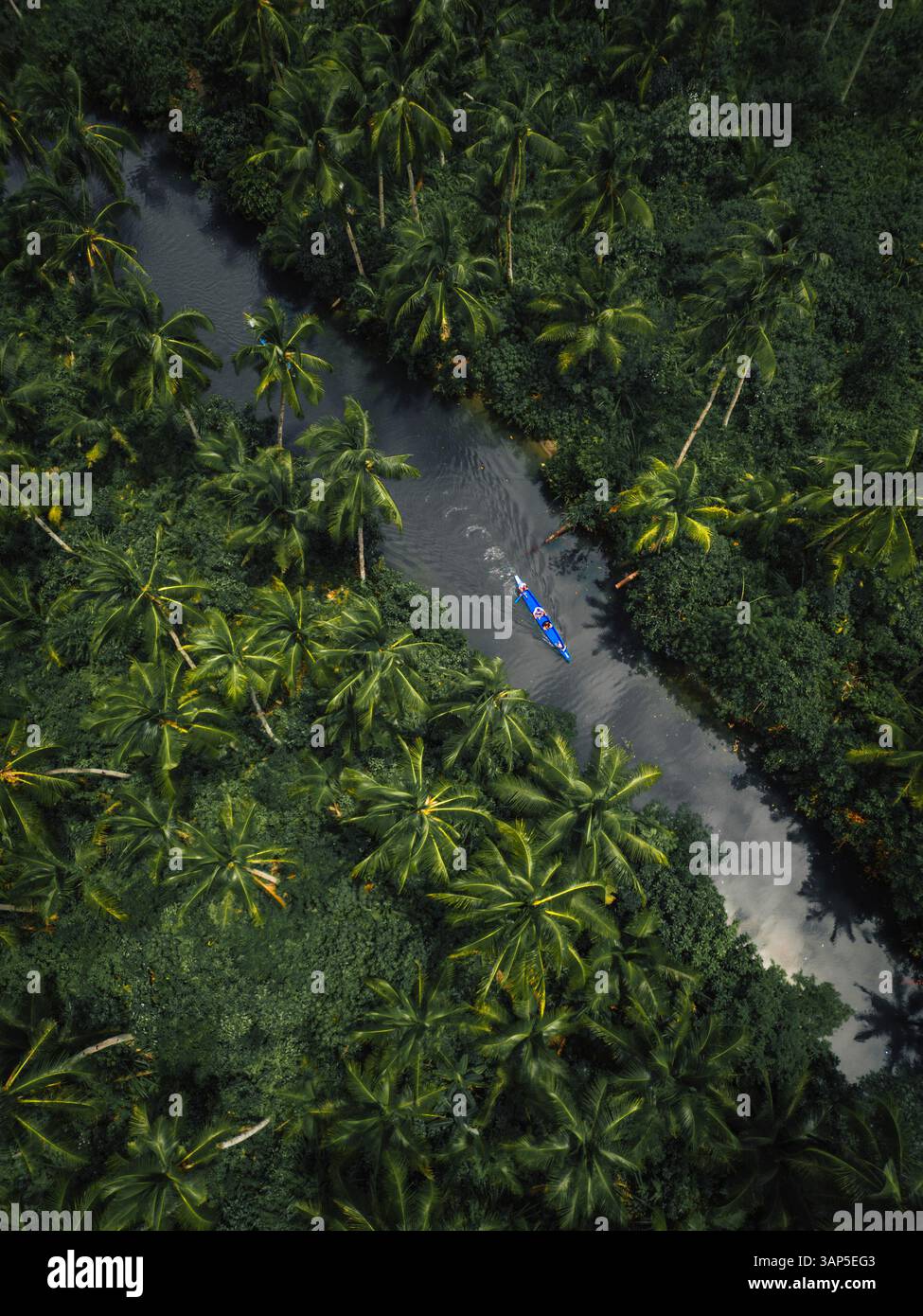 Vista aerea con droni di una canoa che naviga lungo il fiume tropicale a Siargao Island, Dapa, Surigao del Norte, Filippine. Foto Stock