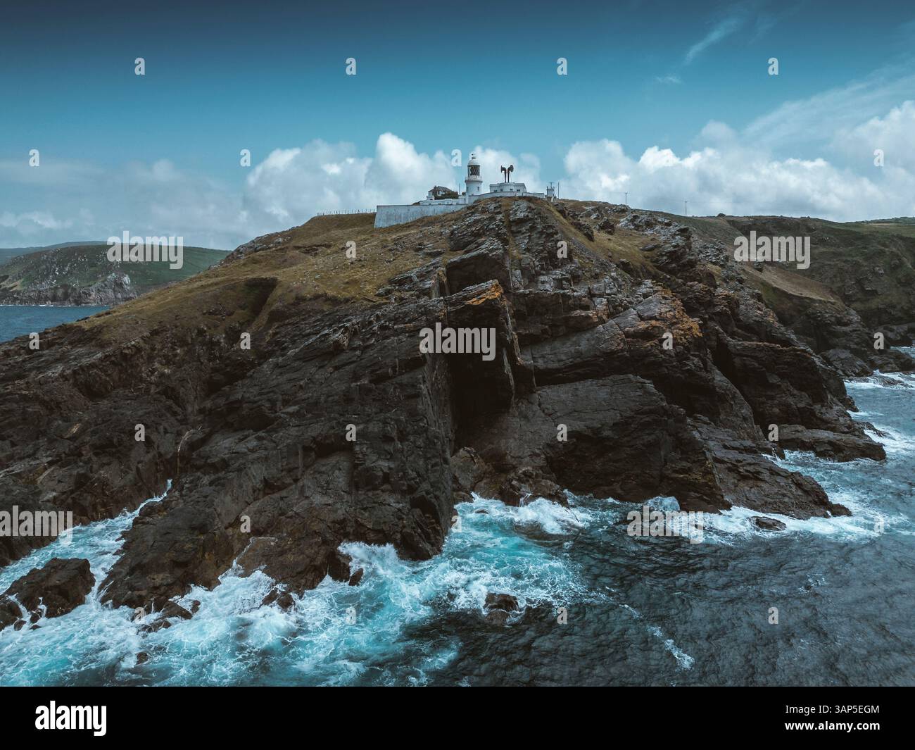 Vista aerea di un faro spettacolare su una scogliera aspra che si affaccia sulle onde selvagge dell'oceano, Pendeen, Inghilterra. Foto Stock