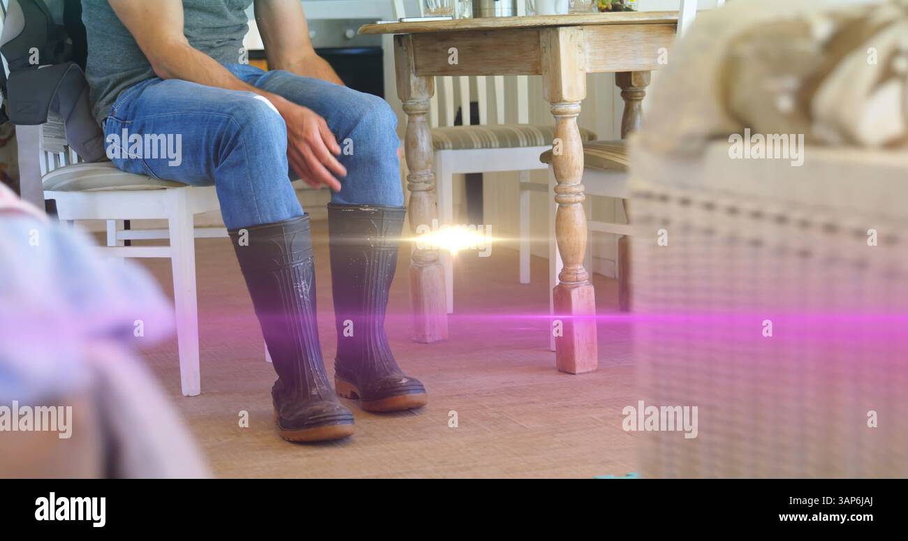 Immagine della luce sulla parte bassa dell'uomo in cucina che indossa stivali wellington Foto Stock