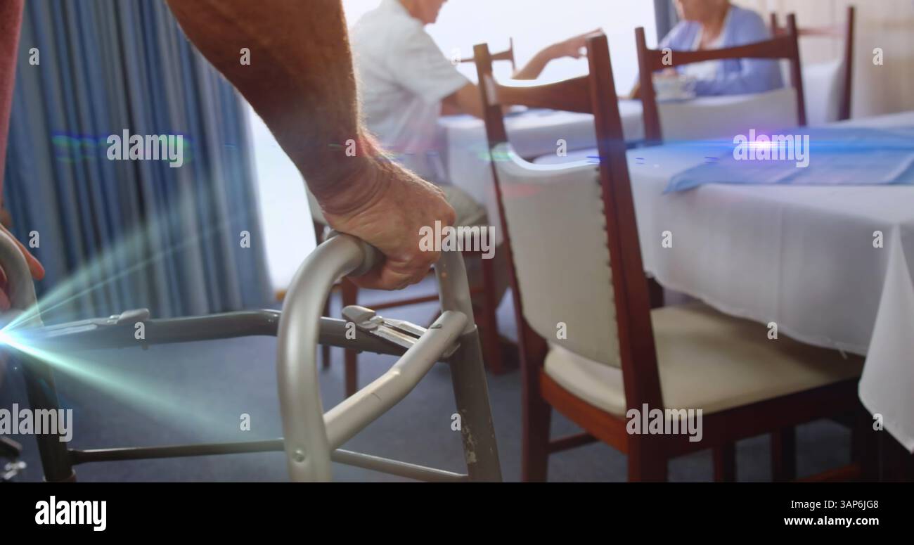 Immagine della luce che si muove sopra un anziano nella sala da pranzo utilizzando una cornice per camminare Foto Stock