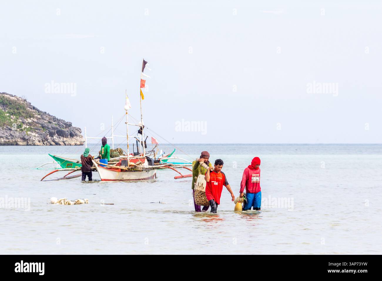 I pescatori che nuotano nelle acque profonde della coscia dalla loro banca trasportano le loro catture fresche a Isla Gigantes, Filippine, una rinomata comunità di pescatori Foto Stock