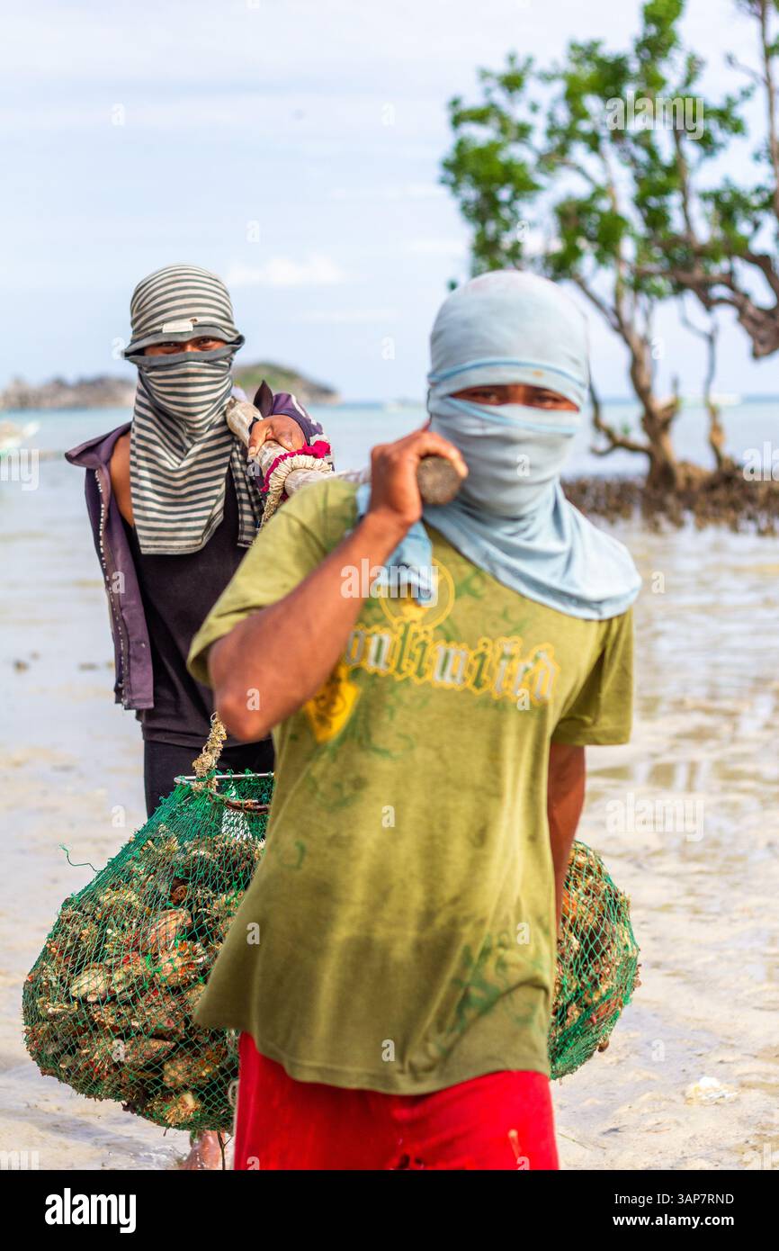 Pescatori filippini che trasportano conchiglie di capesante raccolte da barca a riva nelle isole Gigantes, Iloilo, Filippine Foto Stock