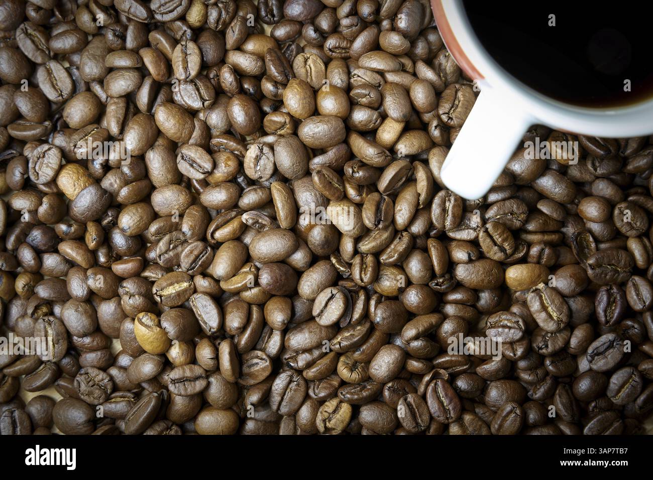 Chicchi di caffè tostati e una tazza di caffè su un tavolo Foto Stock