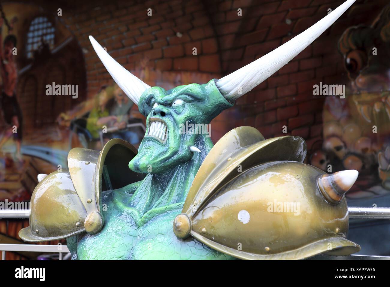 Ritratto di un demone di fronte a un treno fantasma in un piccolo parco divertimenti Foto Stock