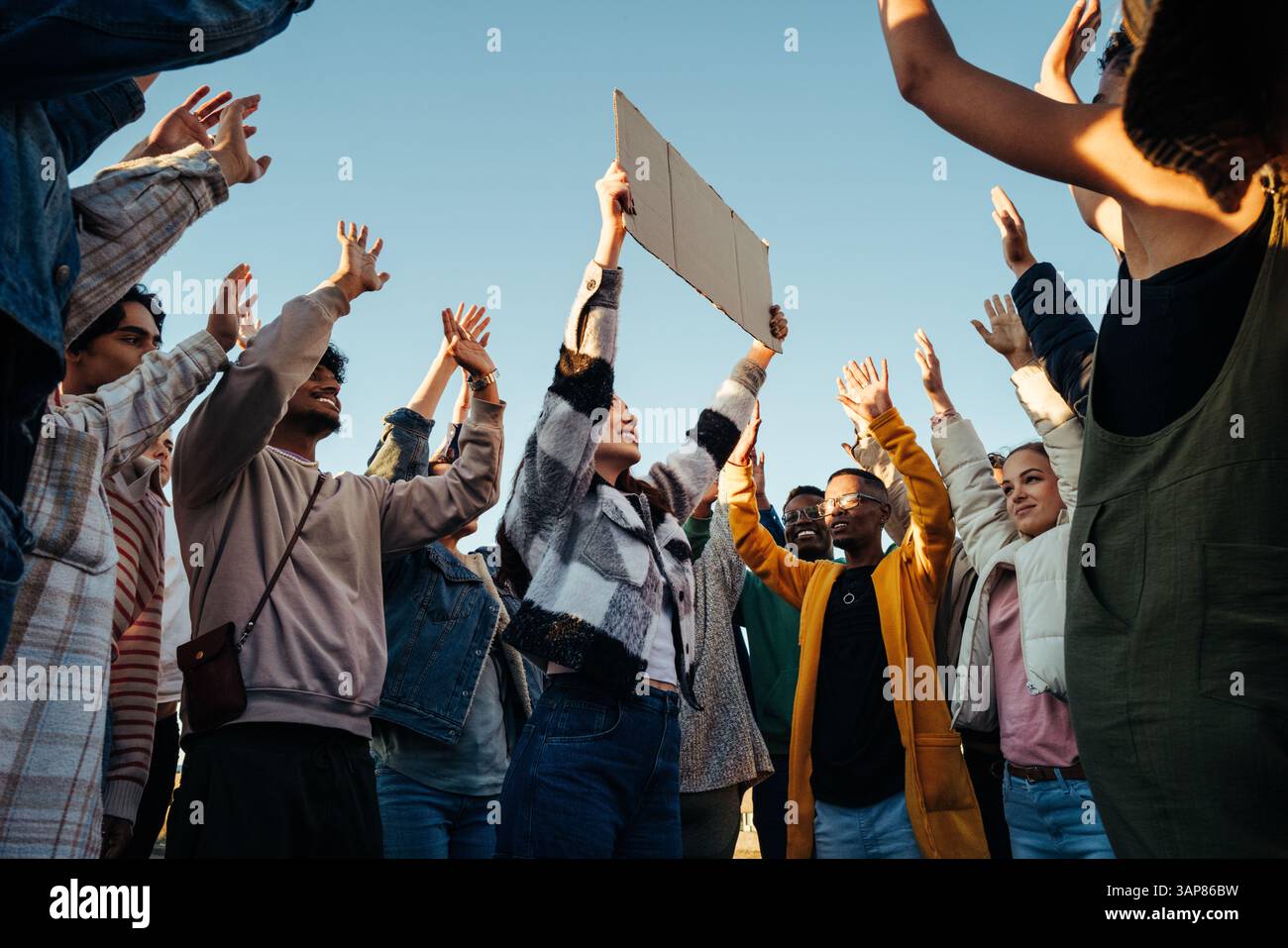 Un gruppo eterogeneo che si riunisce all'aperto, alzando le mani in solidarietà con la giustizia e la dignità per tutti. Dimostra lavoro di squadra, unità, diversit Foto Stock