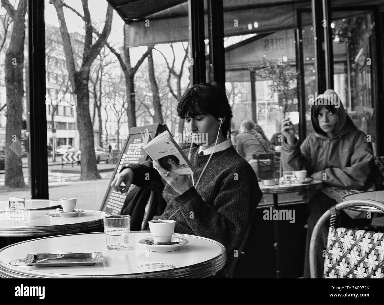 Giovane che legge Orlando di Virginia Woolf in un caffè a Parigi, in Francia, all'inizio della primavera Foto Stock
