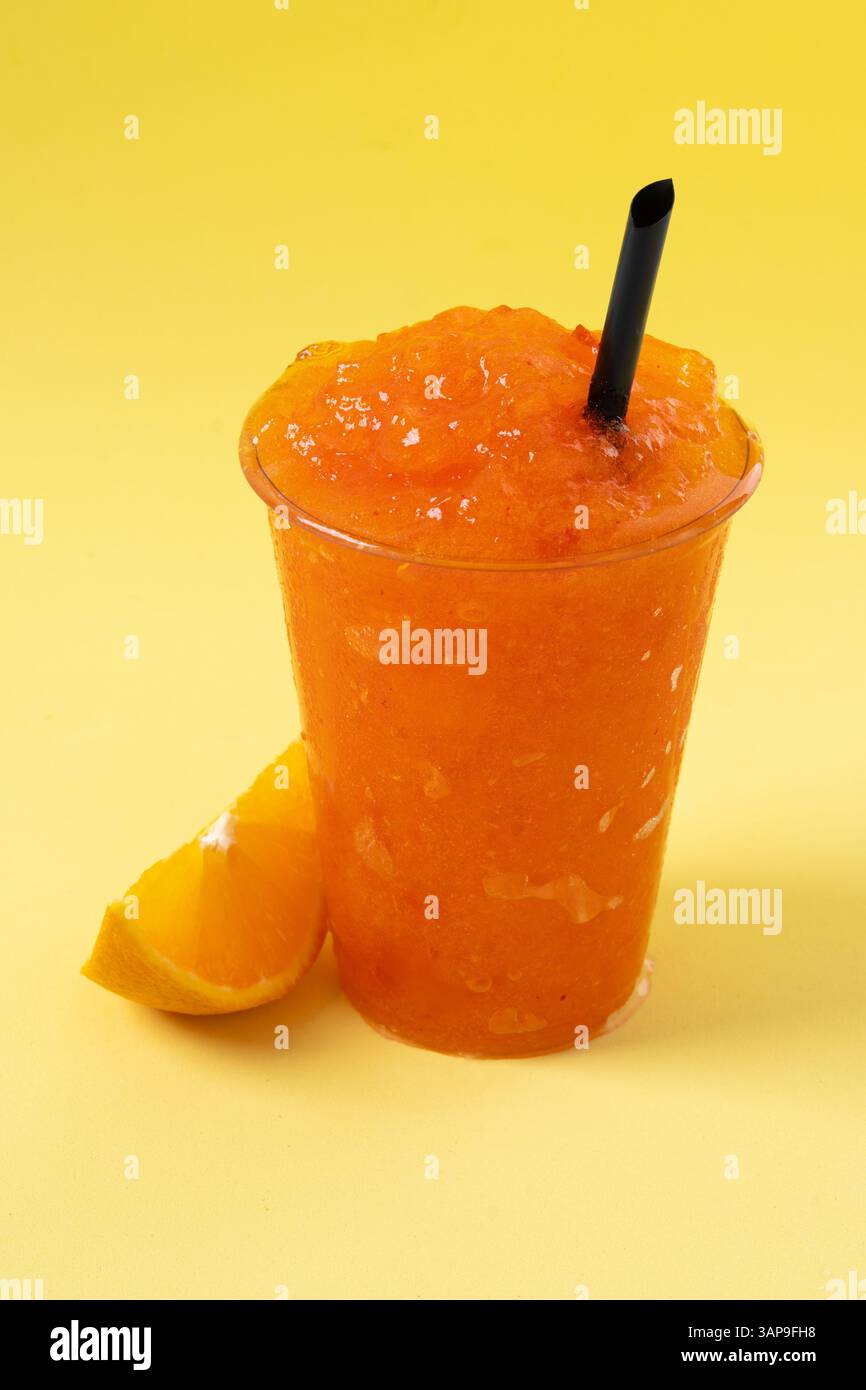 Slushie arancione su sfondo giallo. Foto Stock
