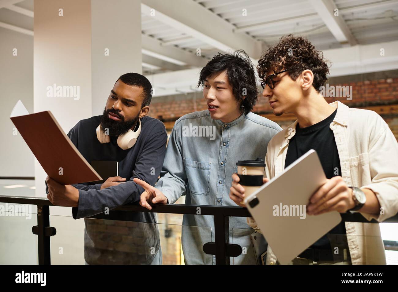 Tre professionisti si impegnano in una discussione collaborativa sui documenti in uno spazio open Office. Foto Stock