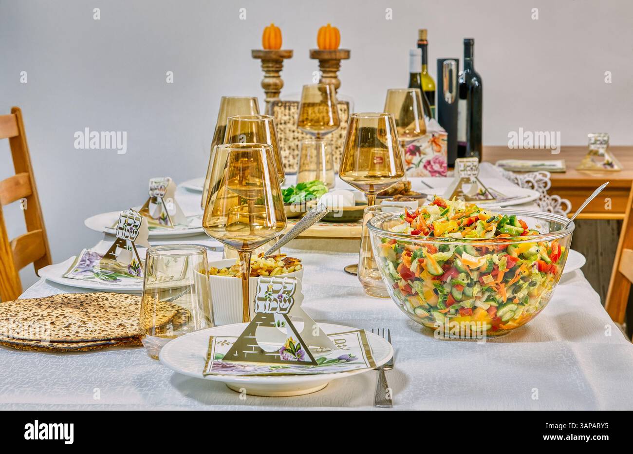 Un tavolo festivo pasquale con cibi simbolici, decorazioni tradizionali e vino, splendidamente preparato per la festa ebraica. Foto Stock