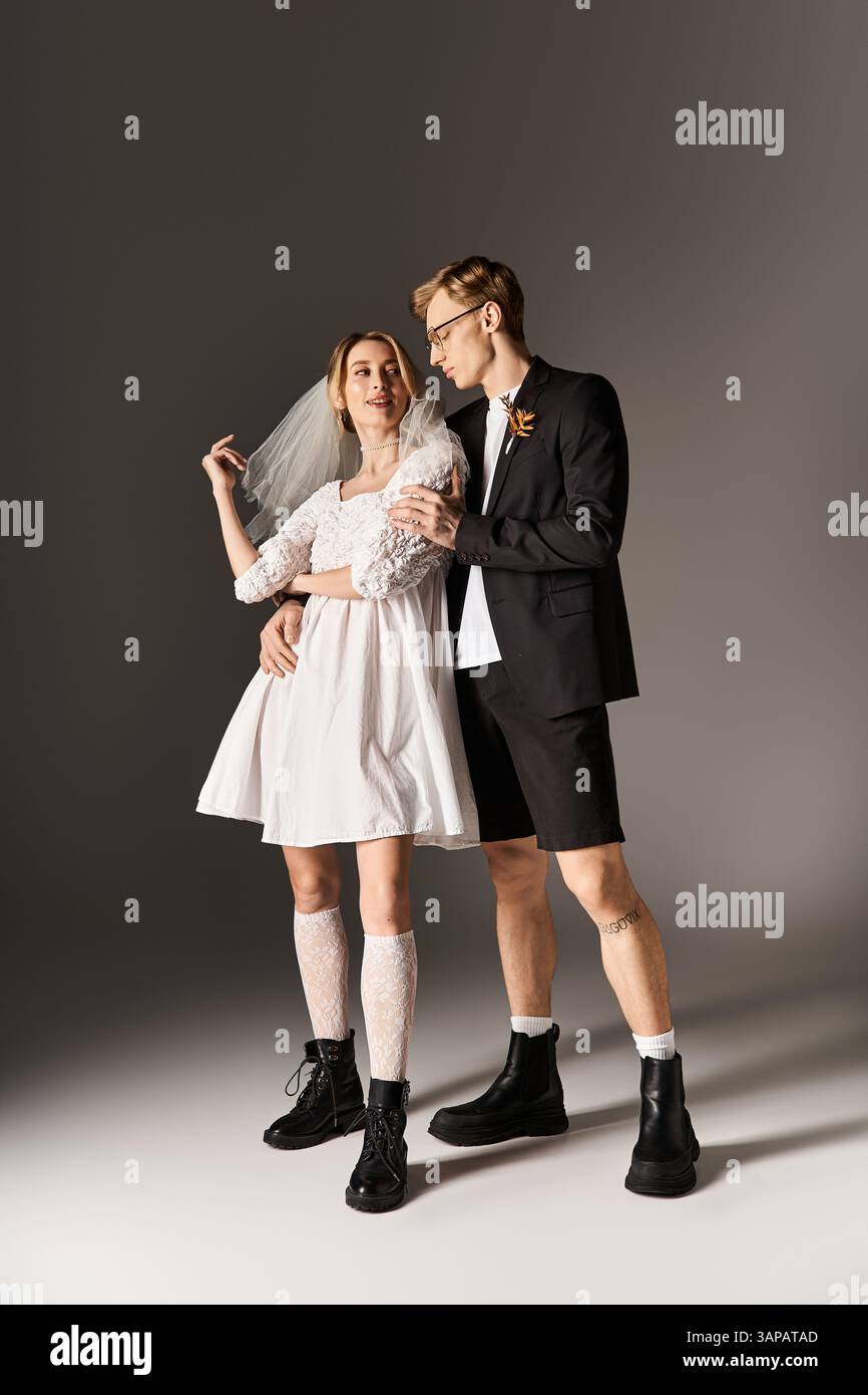 Una giovane coppia abbraccia con gioia, mostrando una miscela di stili di matrimonio tradizionali e moderni. Foto Stock