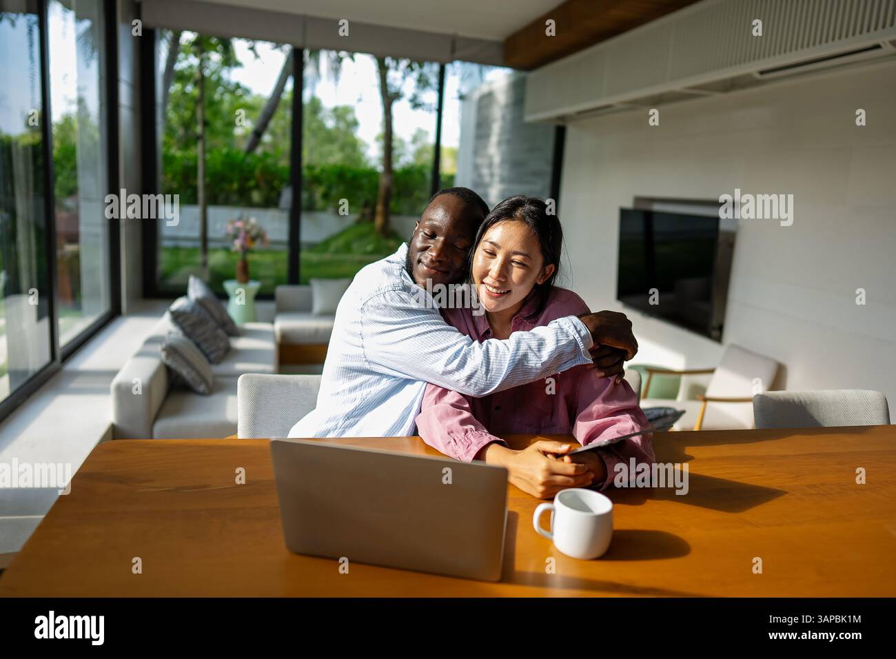 Felice coppia multietnica che utilizza un notebook, acquista online con le vendite, gioca insieme Foto Stock