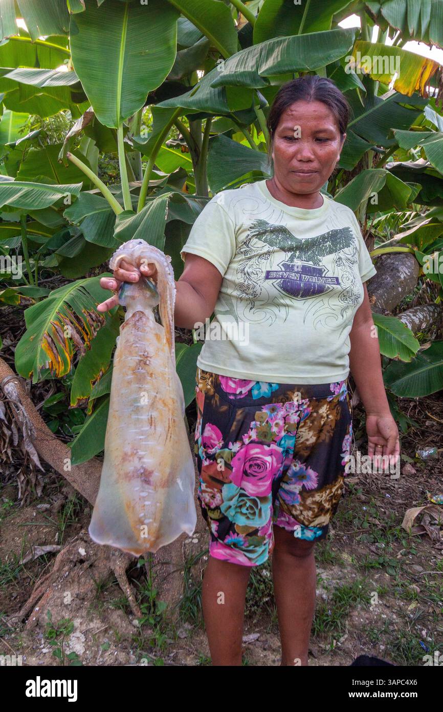 Un venditore di mezza età del mercato filippino che detiene un enorme calamaro in un mercato locale di Iloilo, Filippine Foto Stock