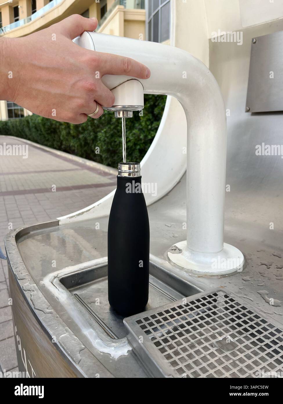 Riempimento della bottiglia d'acqua riutilizzabile presso la stazione dell'acqua pubblica all'aperto. Supporto per l'ecologia, sostenibile negli ambienti urbani Foto Stock