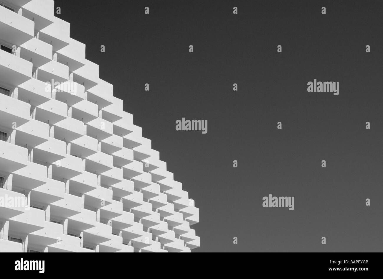 Una facciata bianca dell'hotel contro un cielo scuro per un monocromo contrastante Foto Stock