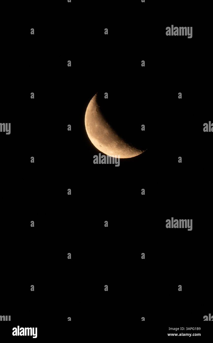 Primo piano di una luna crescente in cera contro un cielo notturno nero. Crateri dettagliati e superfici Foto Stock