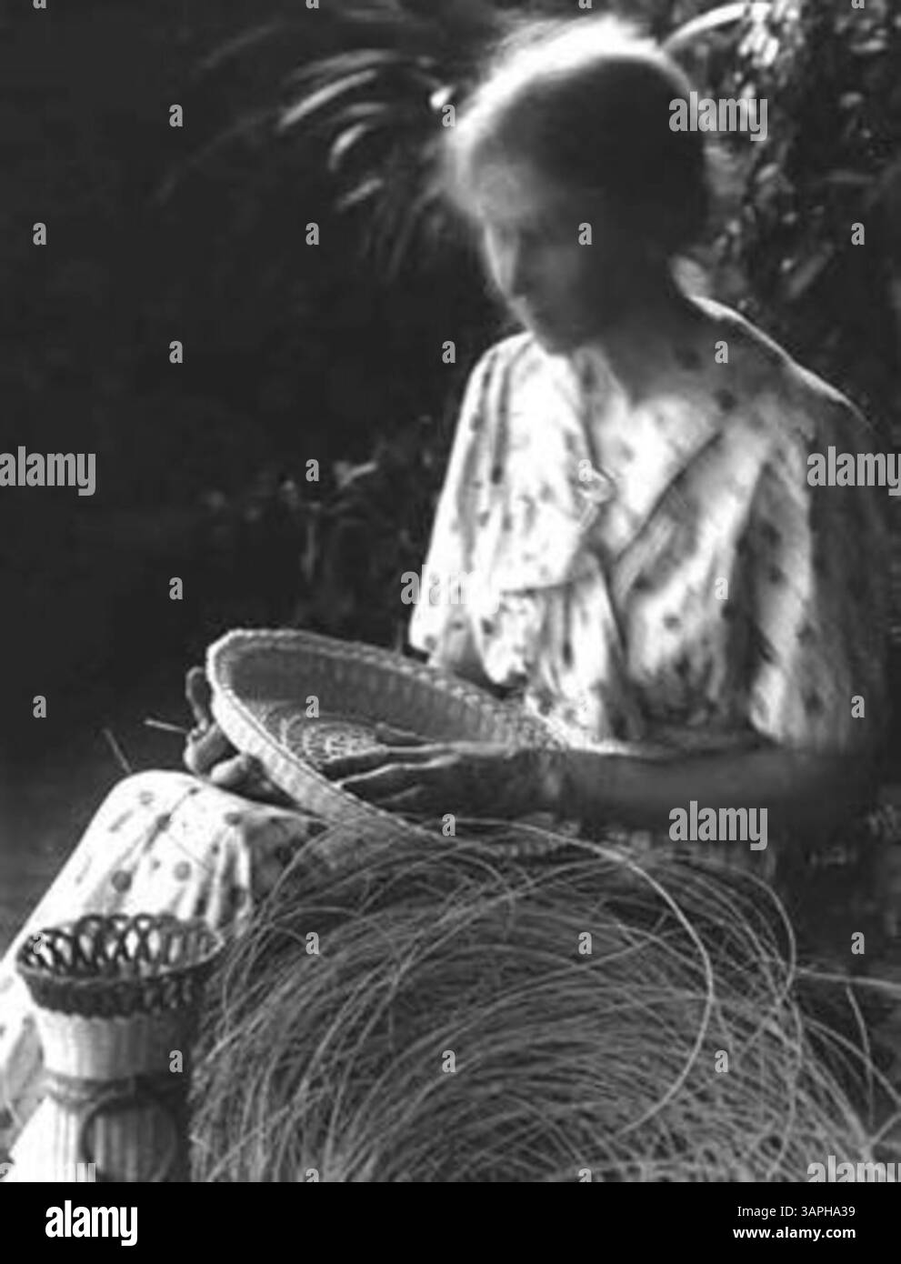 Flora Dysort, un'abile creatrice di cesti, è presente in questa fotografia, che mette in evidenza il suo mestiere come parte dell'arte indigena all'inizio del XX secolo. Foto Stock