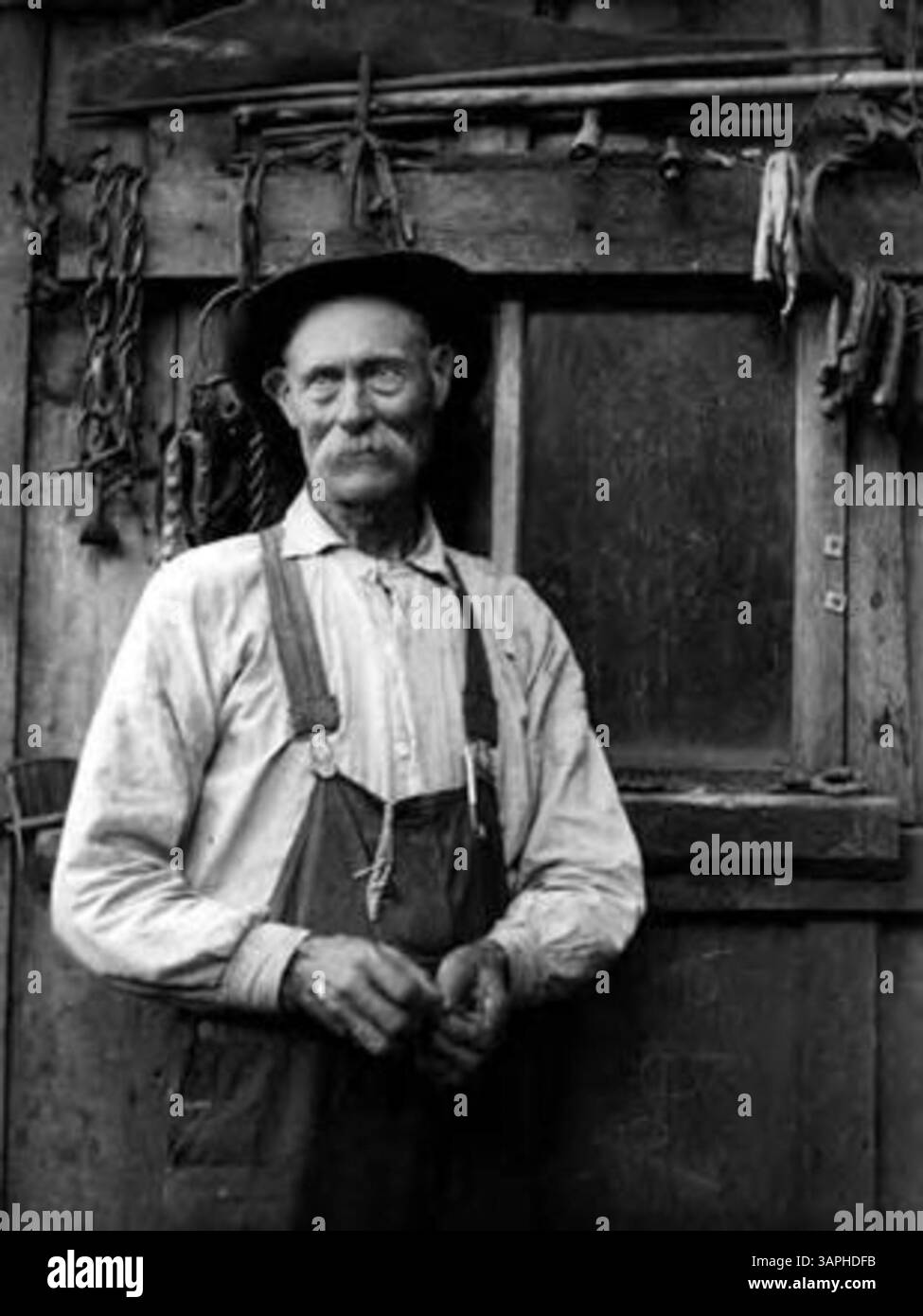 Questa fotografia storica raffigura un uomo all'interno di un capannone, offrendo uno sguardo sulla vita quotidiana e sulle condizioni di lavoro degli individui durante i primi anni del XX secolo. Foto Stock