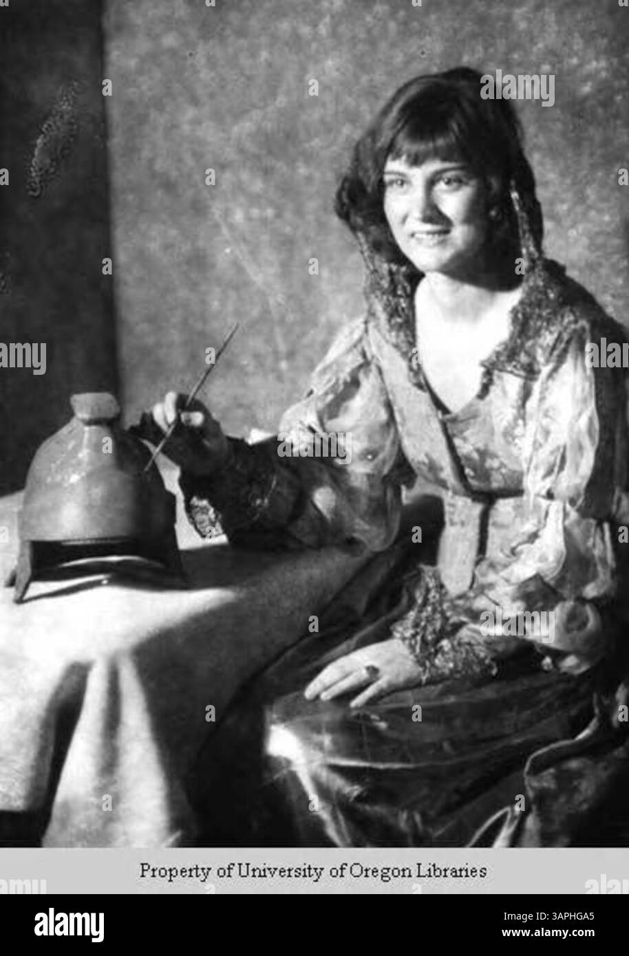 Fotografia della signorina Crumlege, una giovane donna con un abito elegante, che dipinge un modello di un casco centurione romano. Presa a Berea, Kentucky. Foto Stock