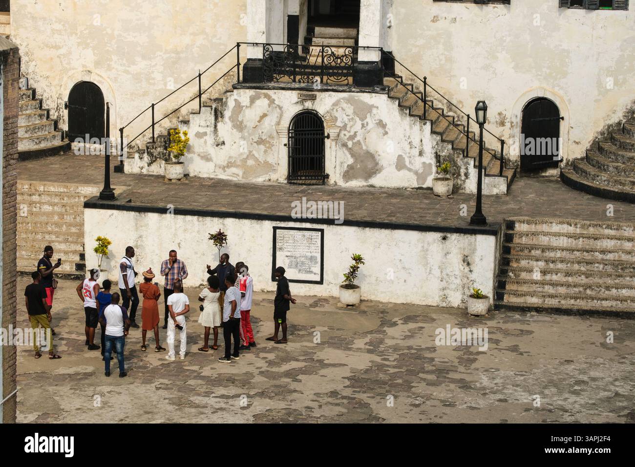Ghana, Elmina. Castello di San Giorgio, castello di Elmina. Turisti africani nel cortile con guida. Foto Stock