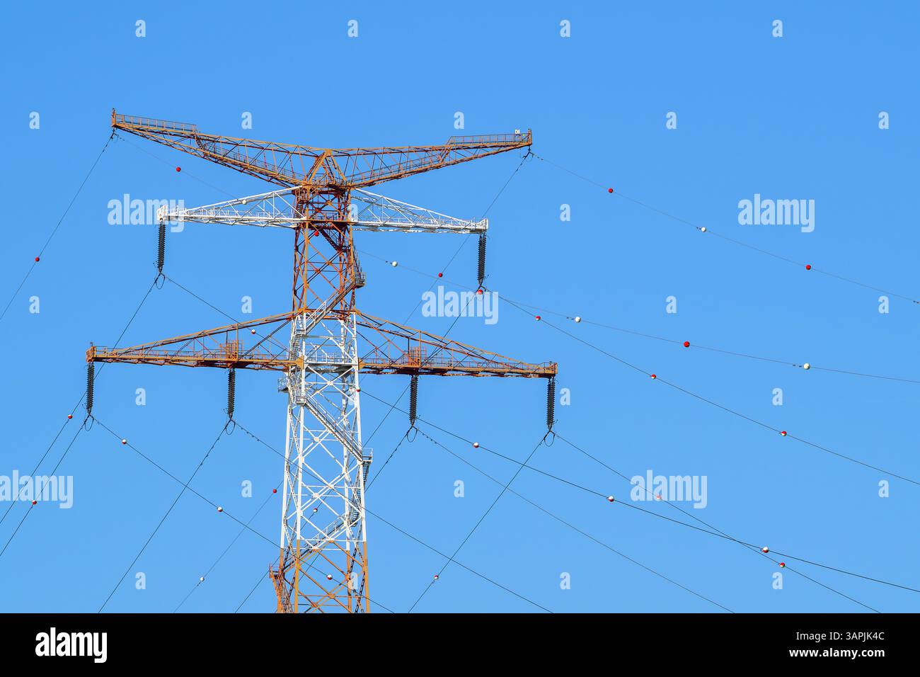 Traliccio elettrico ad alta tensione / torre di trasmissione con isolanti modulari di sospensione e linee ad alta tensione con sfere di marcatura rosse e bianche Foto Stock