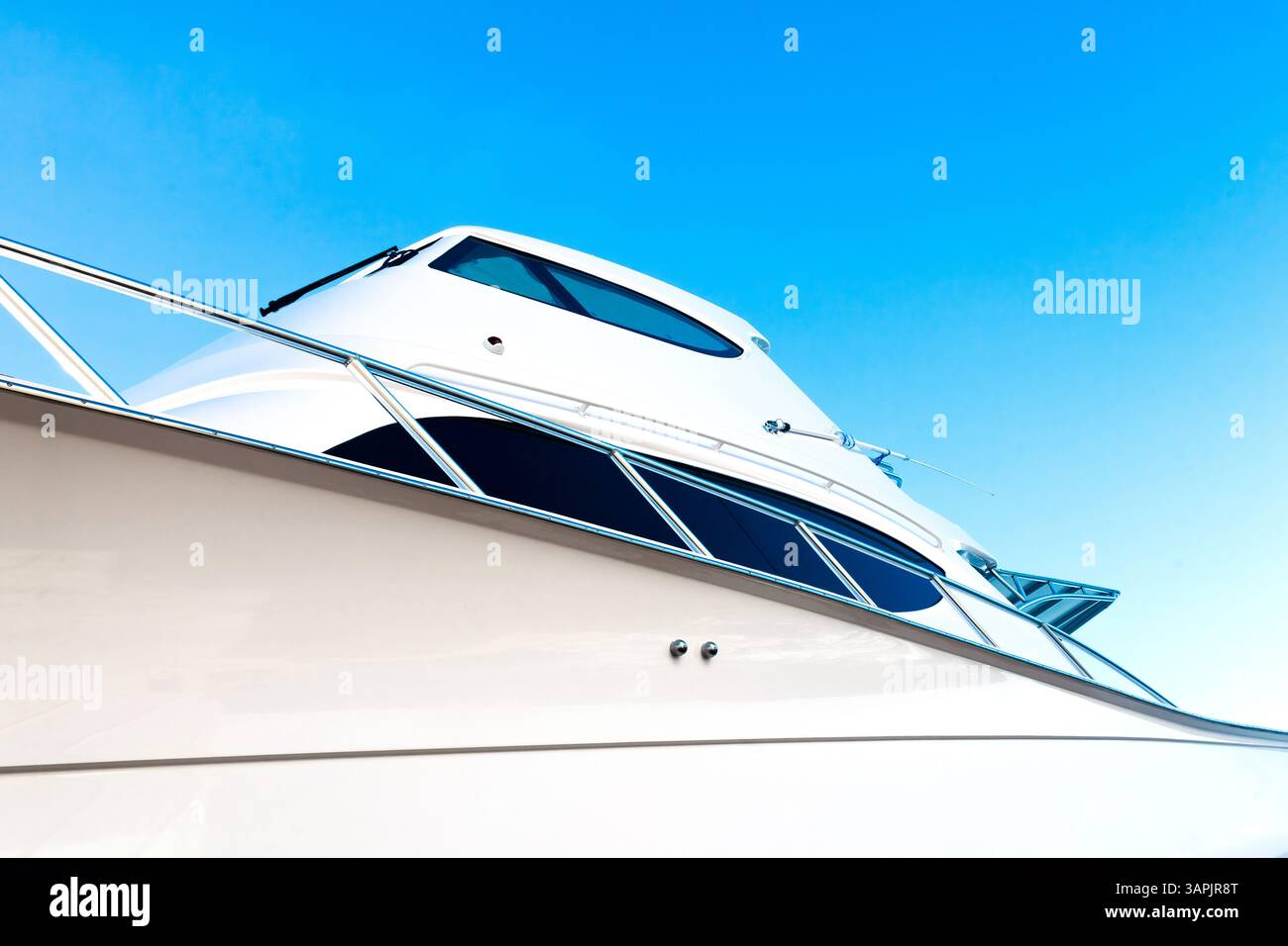 Lo scafo di un lussuoso yacht a motore, contro il cielo blu e la luce del sole nell'angolo, vista dal basso. Foto Stock