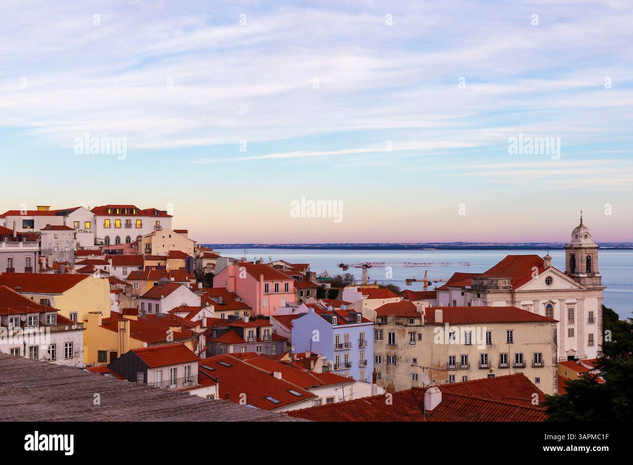 Tramonto su Alfama da Miradouro das portas do sol punto panoramico che mostra case tradizionali con tetti rossi nel quartiere più antico di Lisbona. Foto Stock