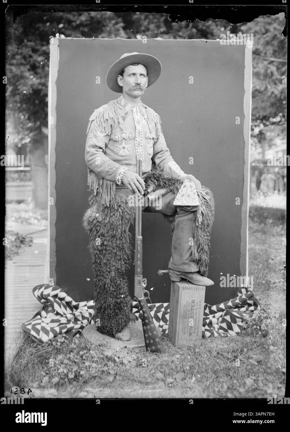 Questo ritratto a figura intera di Lee Moorhouse mostra Munshang il cowboy in costume, con in mano un fucile. L'immagine cattura un cowboy in un abbigliamento d'epoca, mostrando la cultura occidentale. Foto Stock