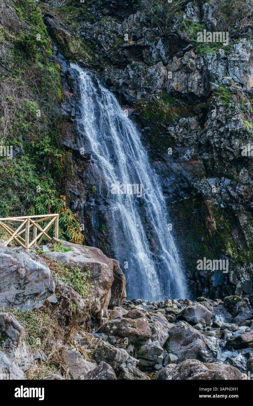 Una splendida cascata si snoda graziosamente lungo le verdeggianti scogliere di Sao Jorge, Azzorre, Portogallo. Un ambiente tranquillo e pittoresco di bellezza naturale Foto Stock