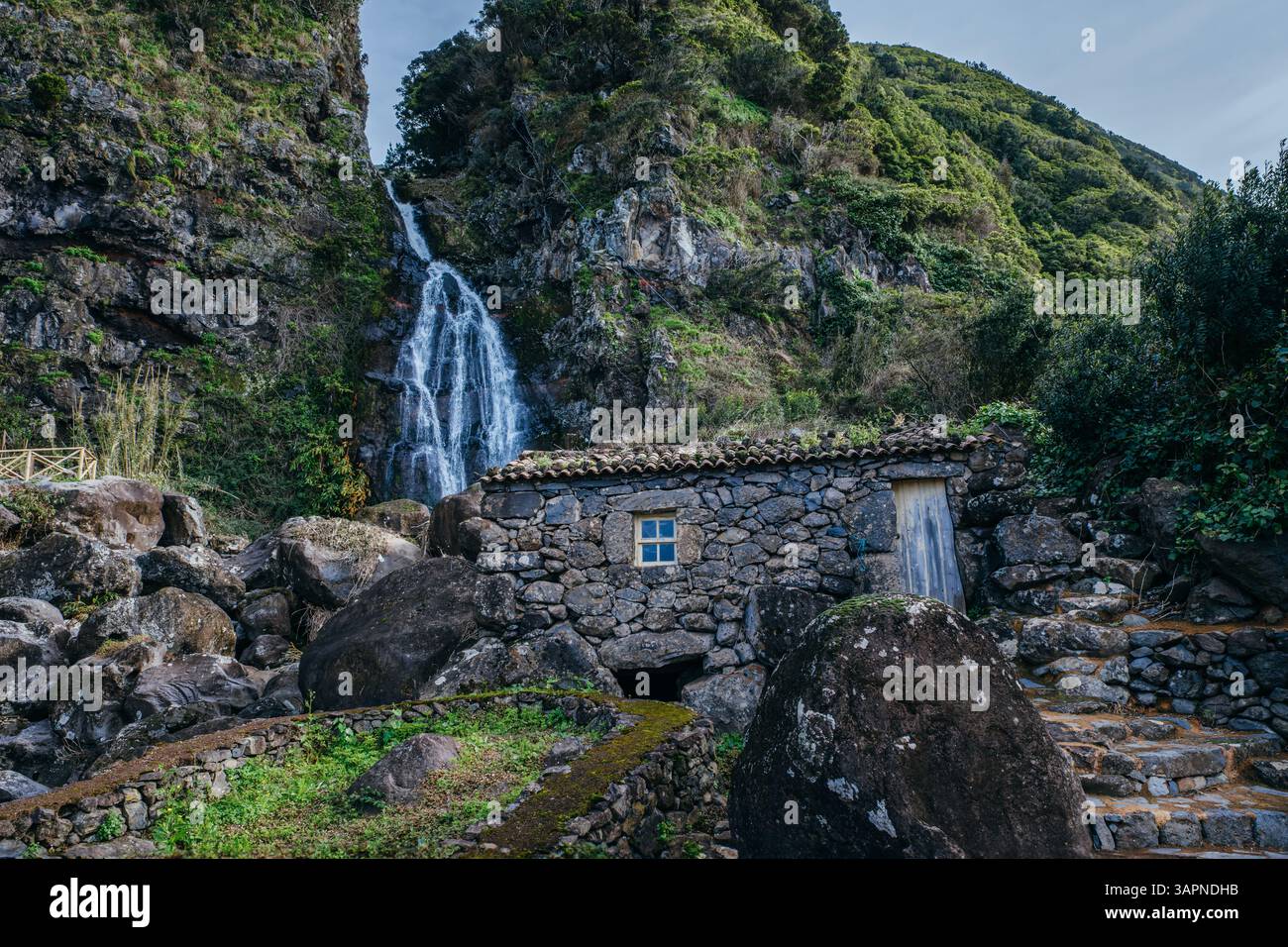 Incantevole Casa in pietra presso la cascata Cascade: Rovine storiche a Sao Jorge, Azzorre, Portogallo. Fascino rustico tra bellezza naturale e paesaggio lussureggiante Foto Stock