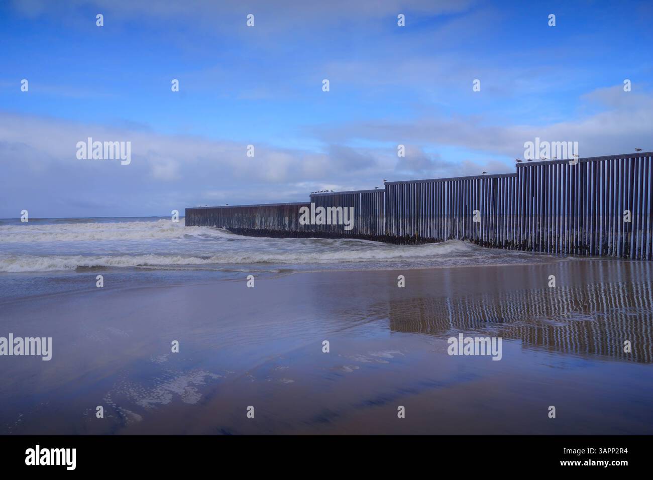 Il muro di confine nella città messicana di Tijuana, la barriera USA-Messico, va nell'oceano: Un famoso simbolo della migrazione in America. Foto Stock