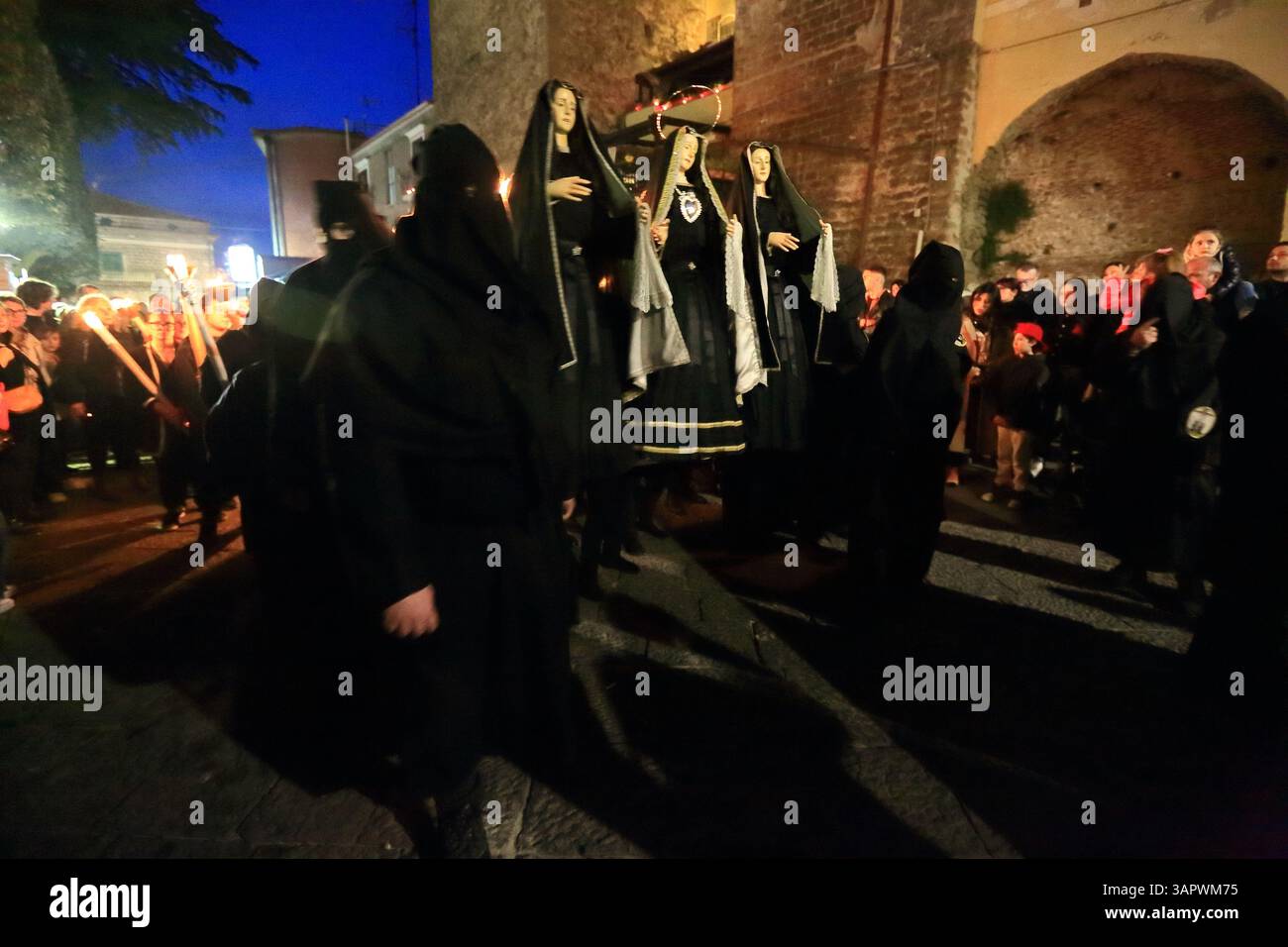 Le persone vestite di nero e con cappuccio sono in processione per le strade del centro storico la sera del venerdì della settimana Santa per celebrare i morti . Foto Stock