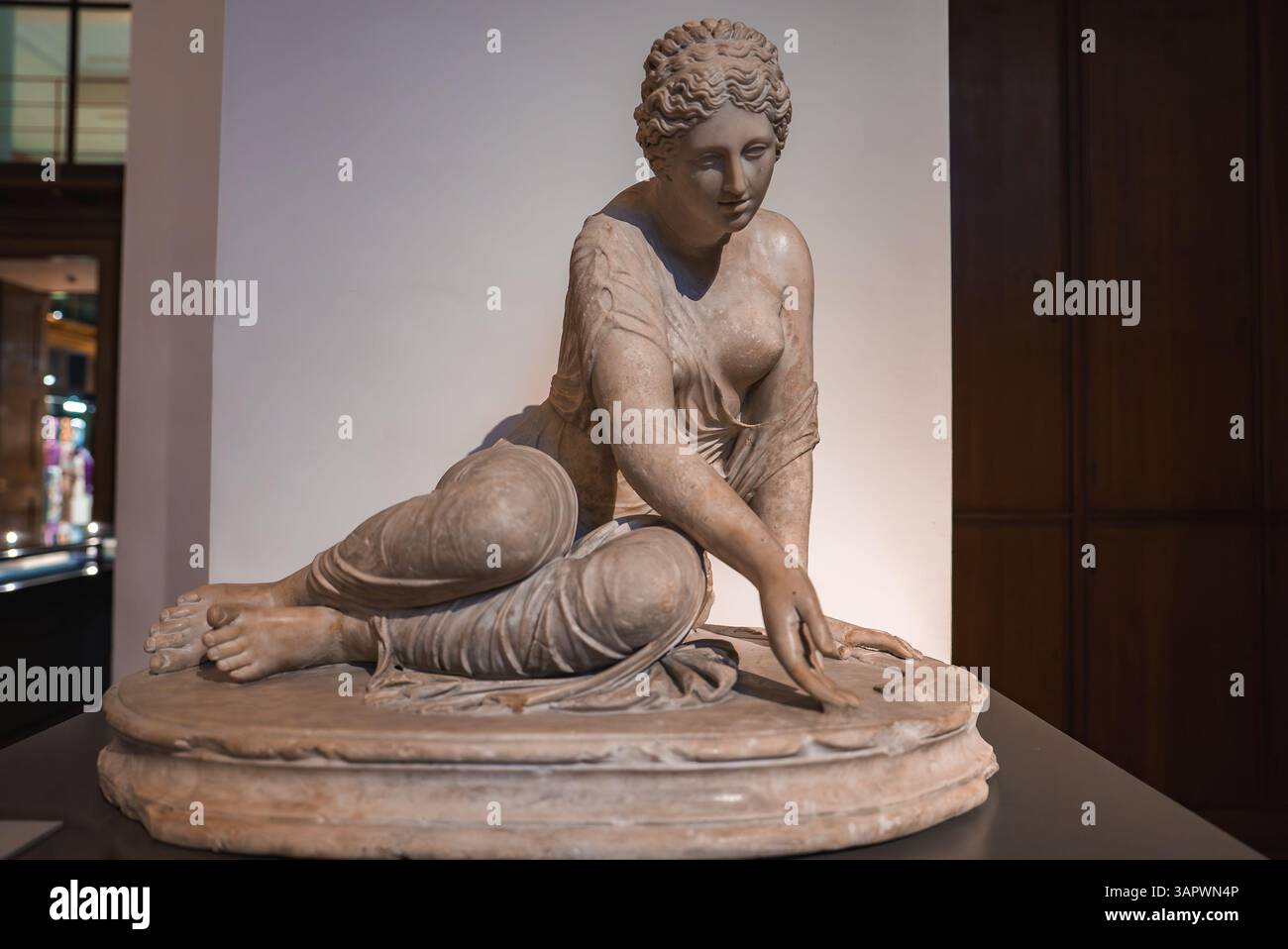 Statua in marmo della donna seduta in un ambiente museale con vetrine Foto Stock