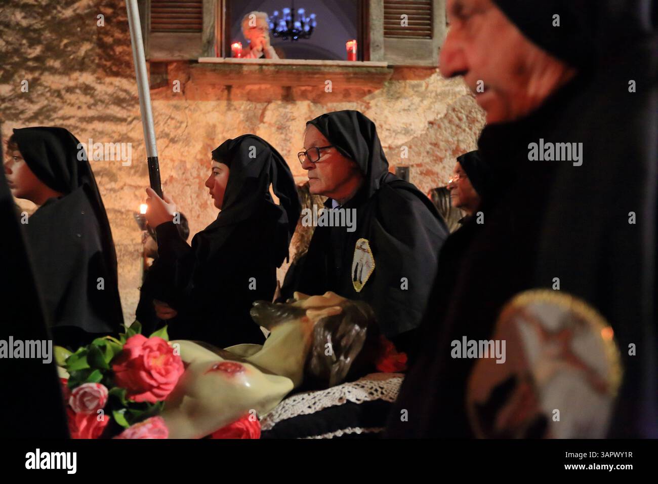 Le persone vestite di nero e con cappuccio sono in processione per le strade del centro storico la sera del venerdì della settimana Santa per celebrare i morti . Foto Stock