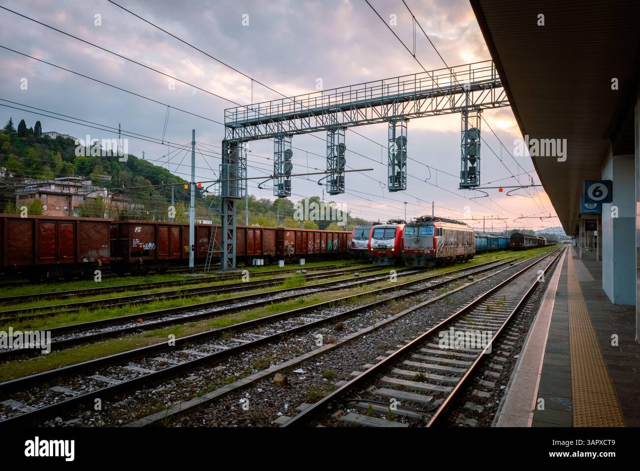 Due treni merci ricoperti di graffiti al tramonto su un binario del cantiere ferroviario Foto Stock
