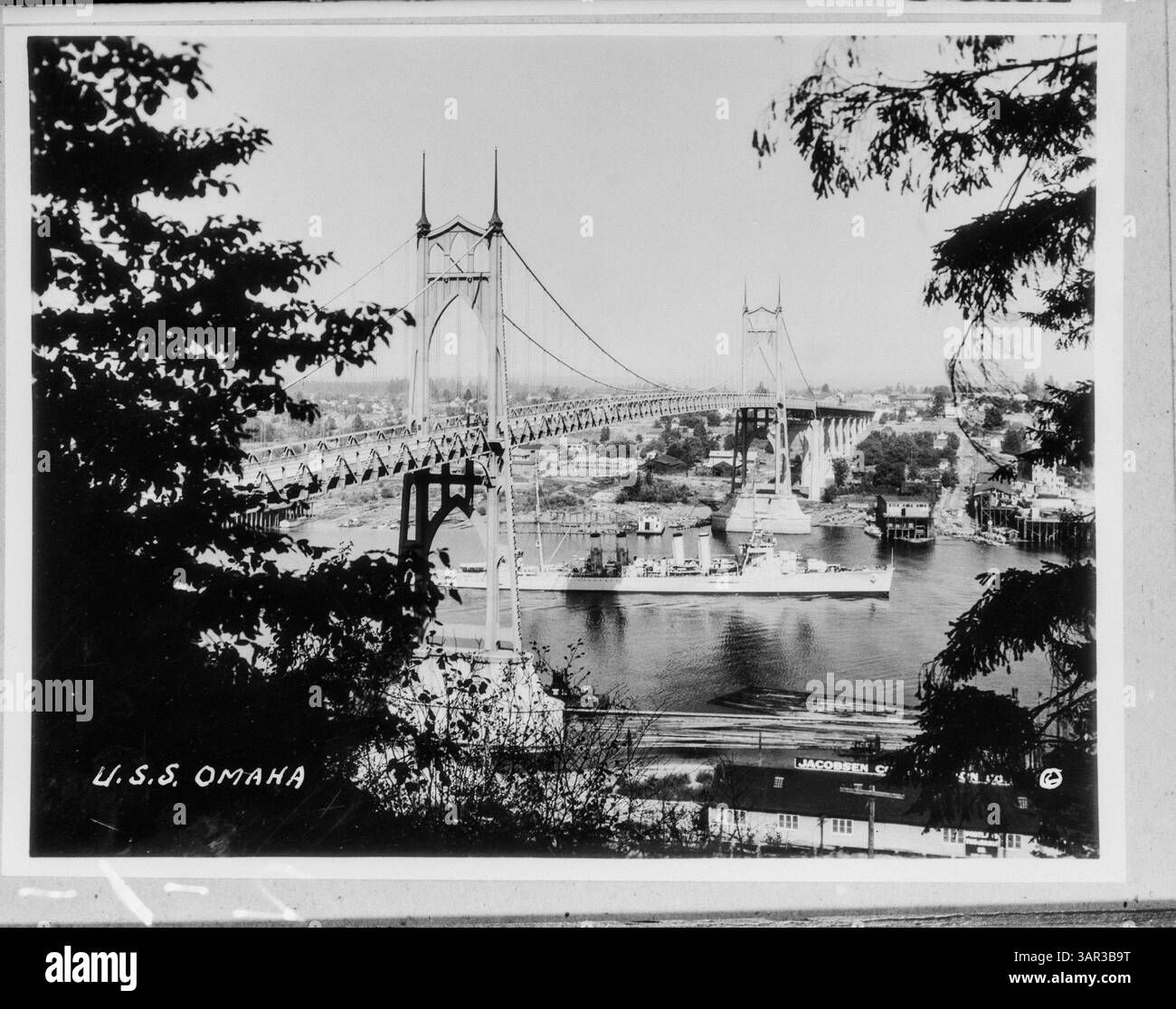 Fotografia della USS Omaha che passa sotto il St. Johns Bridge di Portland. L'immagine cattura il passaggio della nave attraverso l'iconico ponte, con lo skyline di Portland sullo sfondo. Foto Stock