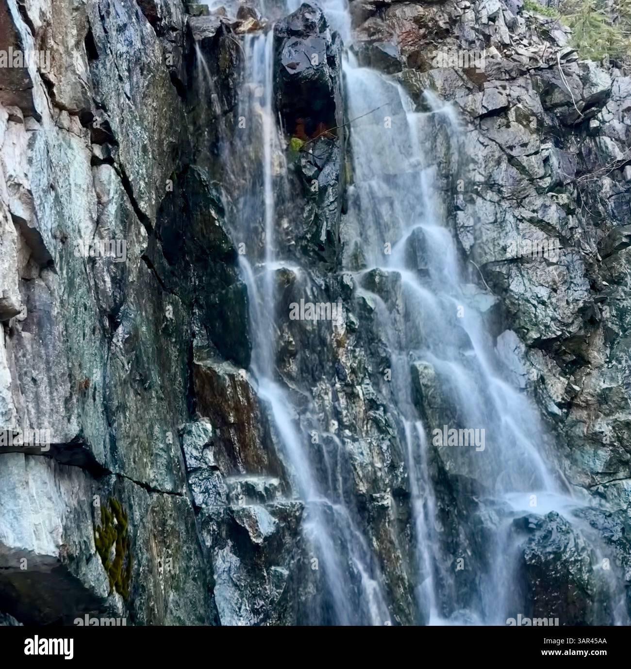 Cascata sottile sopra la ripida parete rocciosa Foto Stock