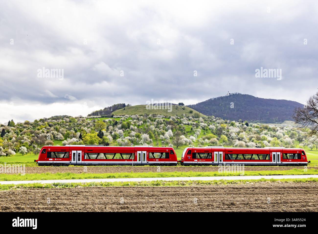 Taelesbahn, ferrovia regionale che attraversa la Lenninger Valley. Primavera sull'Albtrauf dell'Alb Svevo. Alberi da frutto in fiore nei frutteti intorno a te Foto Stock