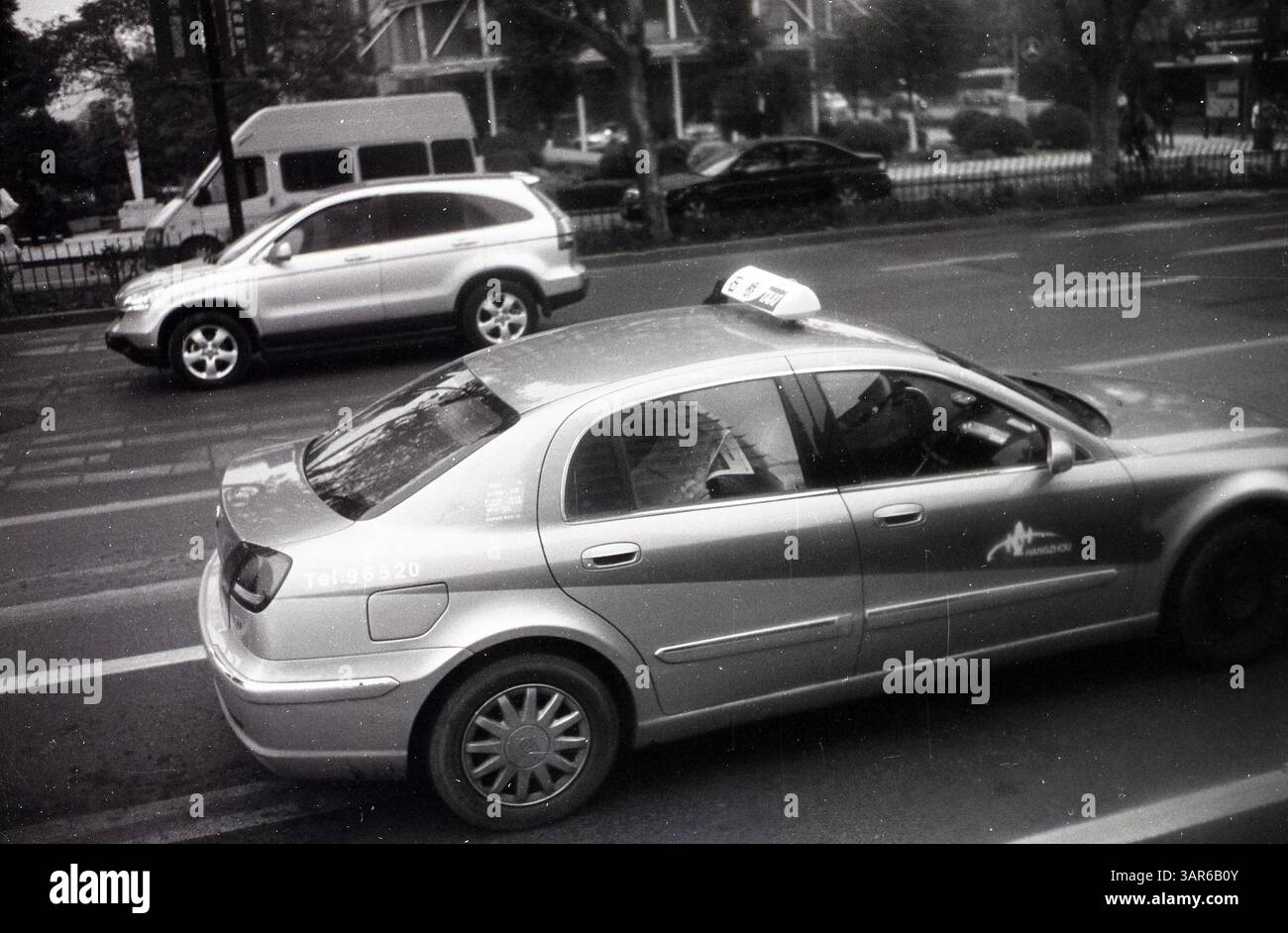 Passeggero che legge un giornale in un taxi Motion in una strada trafficata a Hangzhou - momento urbano tranquillo nei primi anni '2000, Hangzhou, Zhejiang, Cina Foto Stock