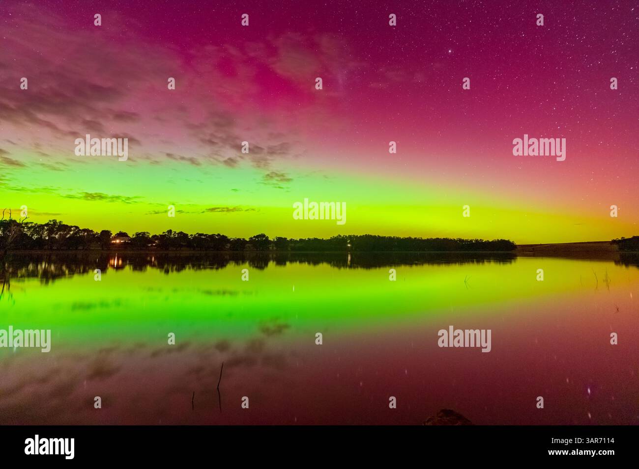 La colorata Aurora Australis si riflette nelle acque tranquille del Cairn Curran Reservoir a Joyces Creek nel Victoria centrale, Australia. Foto Stock
