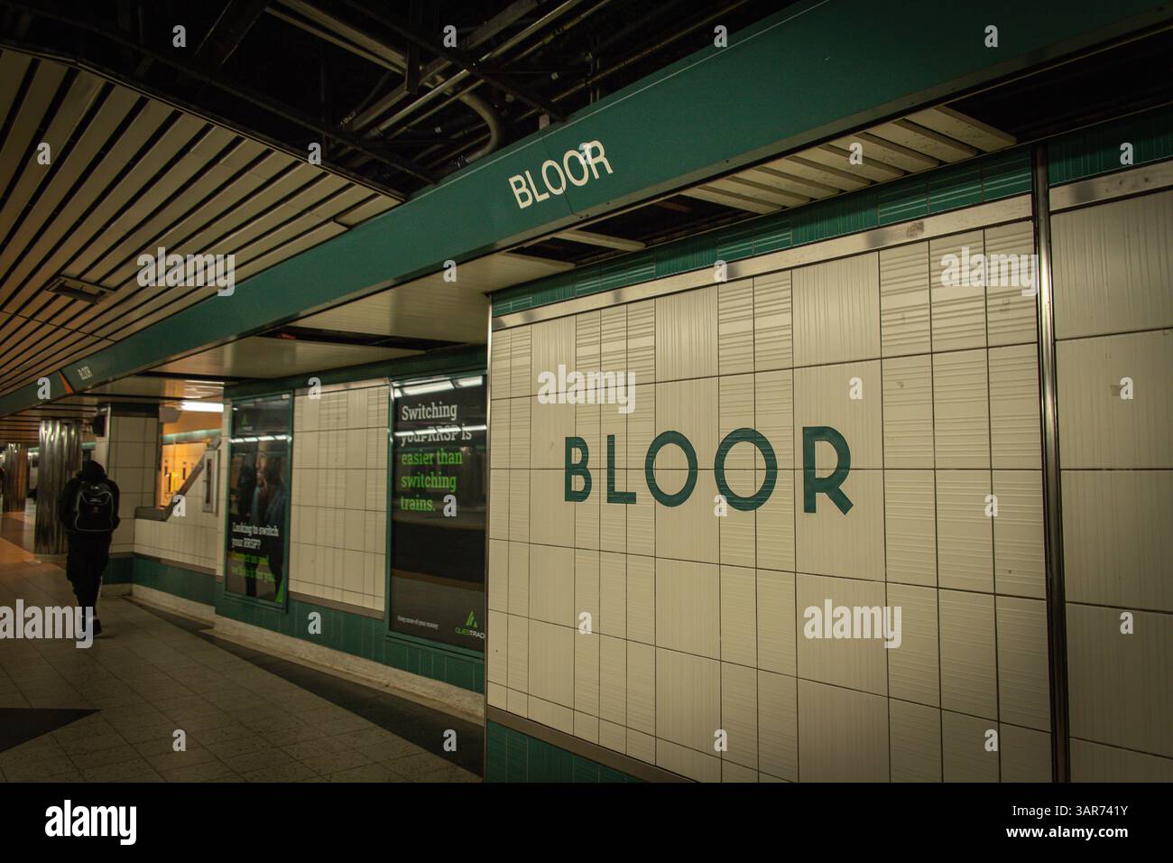 Una vista della piattaforma della metropolitana presso la stazione Bloor di Toronto, caratterizzata da pareti piastrellate, segnaletica della stazione e un pendolare solitario a piedi. Foto Stock