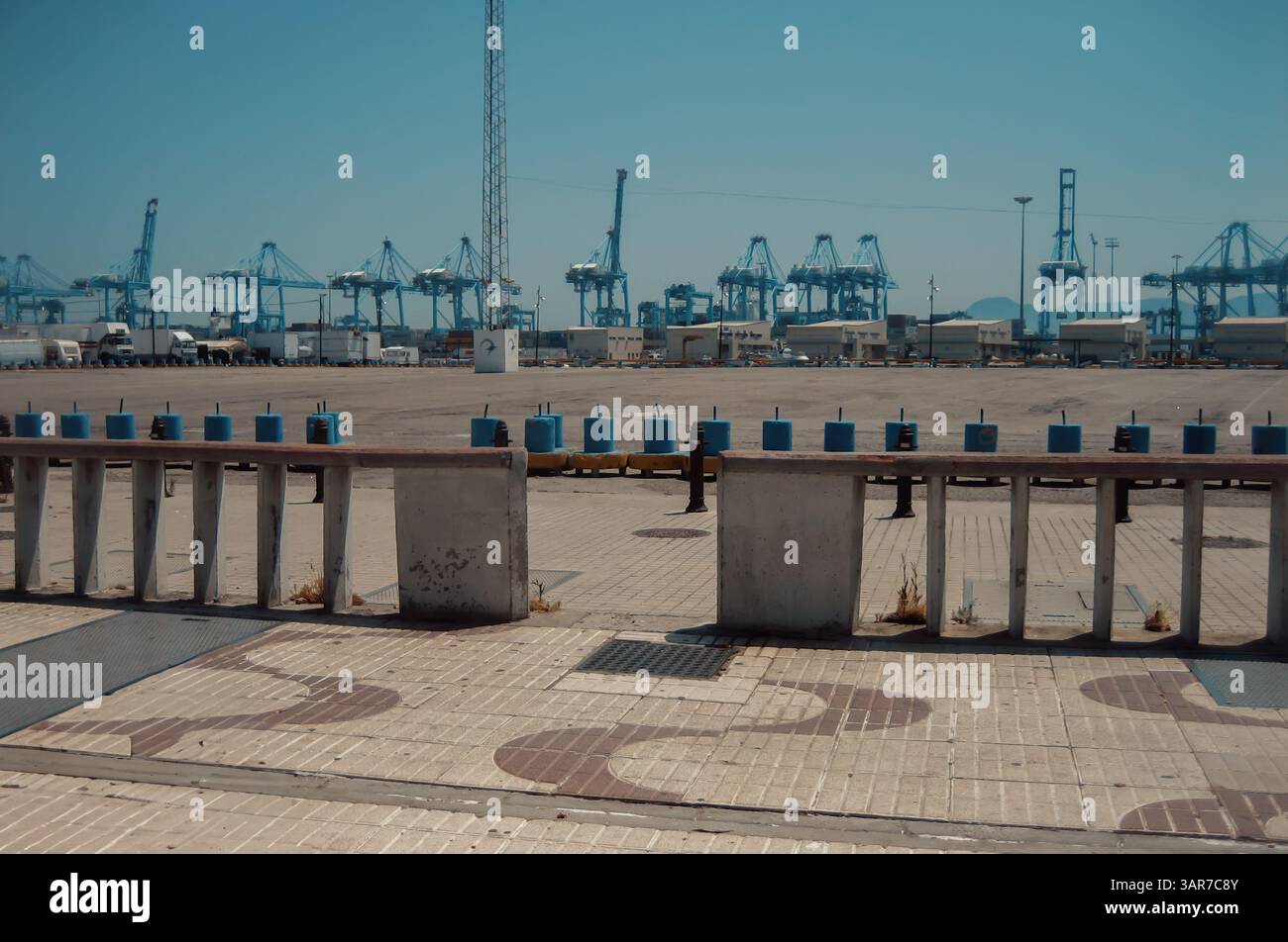 Le gru cargo blu si stagliano su un cielo limpido, affacciate su una vasta area portuale industriale, a indicare le operazioni commerciali e logistiche globali Foto Stock