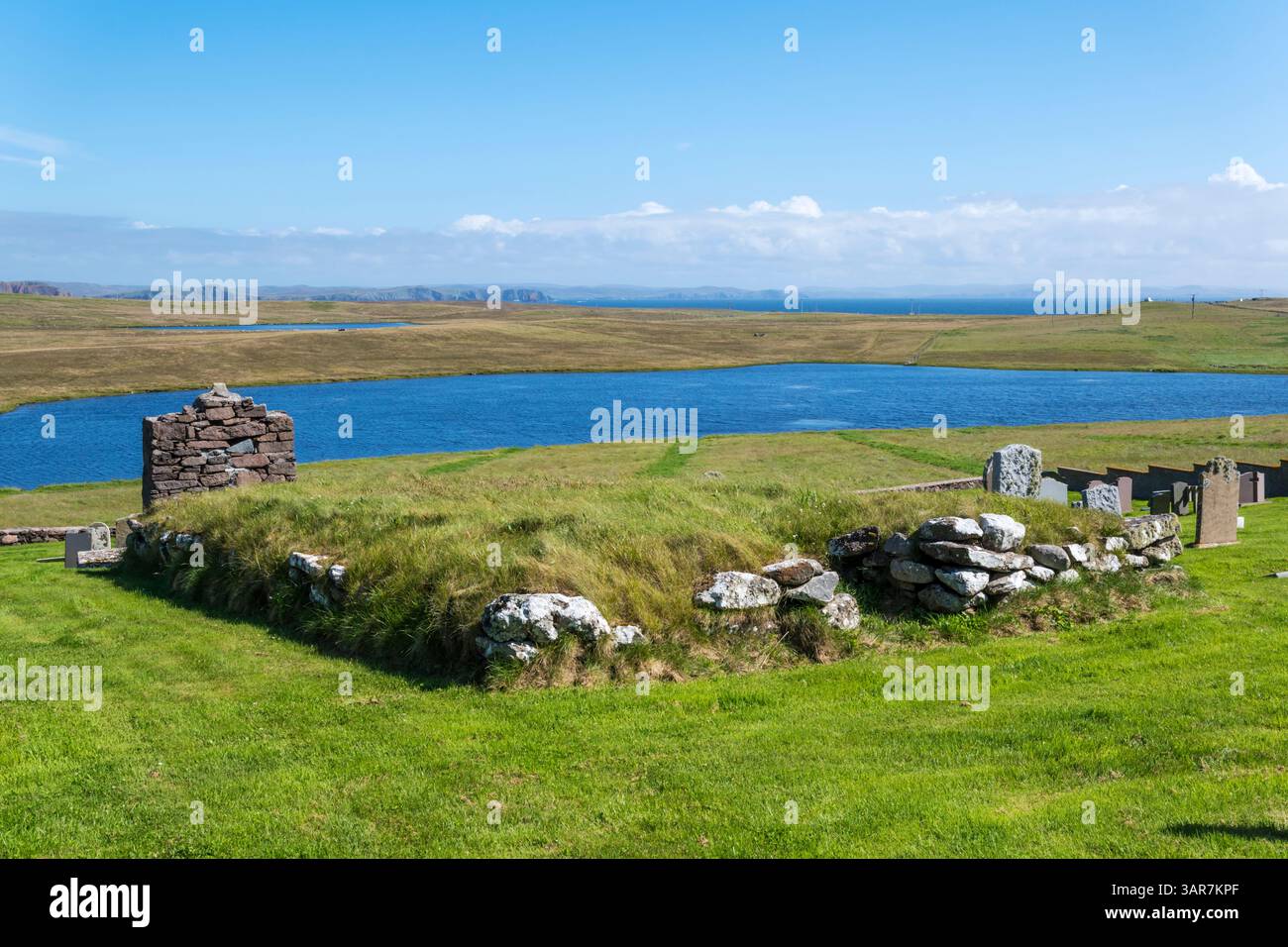Rovine di Cross Kirk nell'Eshaness Old Cemetery a Northmavine sulle Shetland Mainland. Loch di Breckon sullo sfondo. Foto Stock
