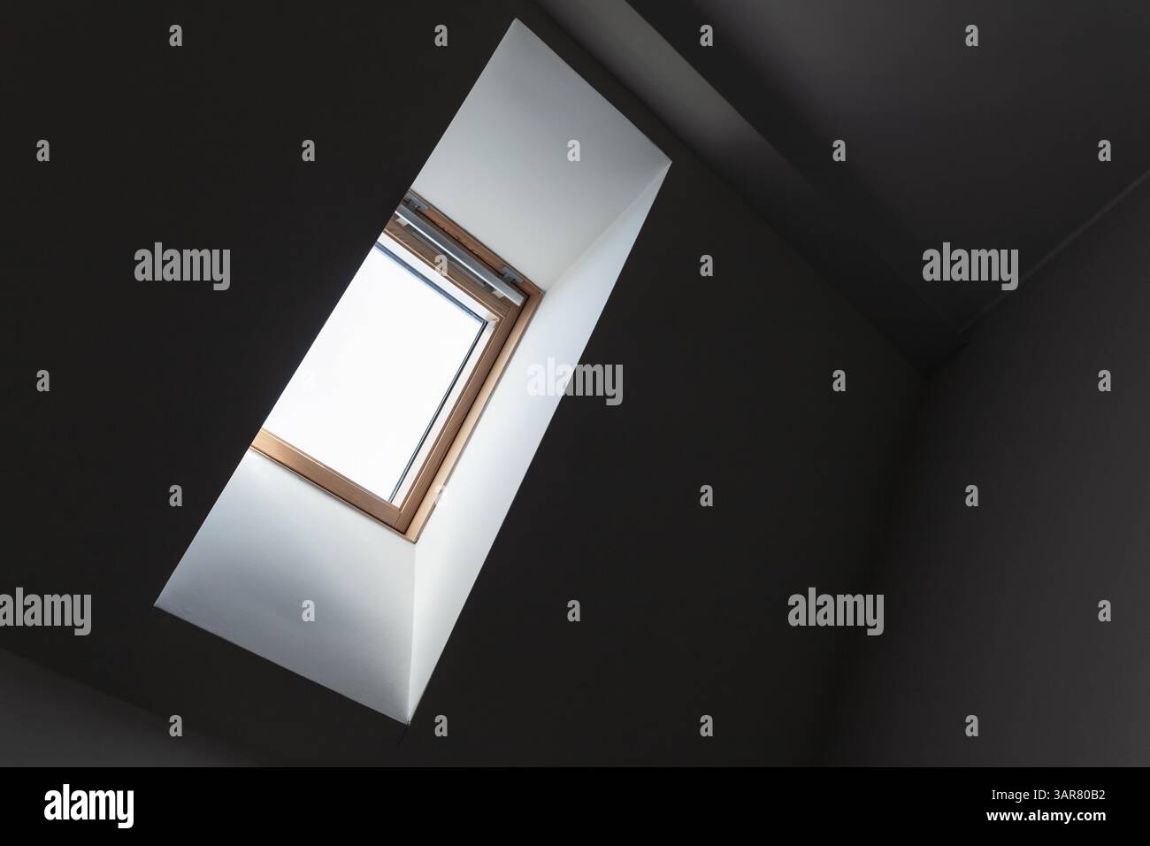 Una finestra lucernario illuminata che cattura la luce naturale, all'interno di un ambiente architettonico pulito e moderno. La struttura è in legno e offre calore Foto Stock