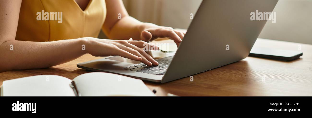 Una giovane donna digita intensamente il proprio notebook in una casa accogliente e accogliente. Foto Stock